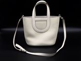 a white purse with a long strap on a black background