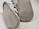 pair of white slippers with black spots on them on top of a bed