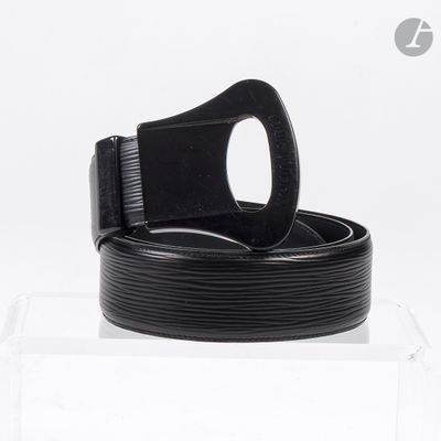 une ceinture noire avec une boucle, posée sur une boîte transparente