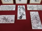 six dessins d'oiseaux encadrés posés sur une table rouge recouverte d'une nappe rouge