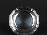 a silver plate on a stand against a black background