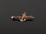 a gold anchor and pearl broochle on a black background