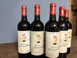 four bottles of red wine are lined up on a wooden table