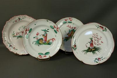 four white plates with red and green designs on them on a table