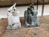 two statues of a woman and a man sitting on a rock