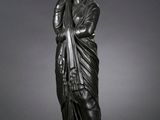 une statue en bronze représentant une femme vêtue d'une robe drapée
