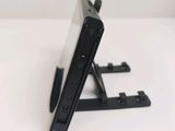 a black cell phone on a stand on a white table