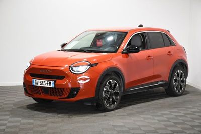 une voiture orange vif garée dans une pièce au sol à carreaux