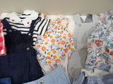 a lot of baby clothes that are laying on a bed