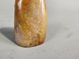 a yellow and brown stone object on a white surface