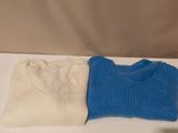 pair of blue and white sweaters sitting on a white table