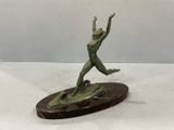 bronze sculpture of a woman jumping on a surfboard on a marble base