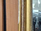 a mirror with a gold frame on a wooden wall