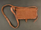an old brown leather purse with a strap on a gray surface