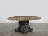 une table ronde avec un plateau en bois et un piètement sculpté