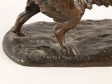 bronze statue of a dog on a rock on a white background