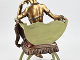 bronze statue of a woman sitting on a chair with her hand on her chin
