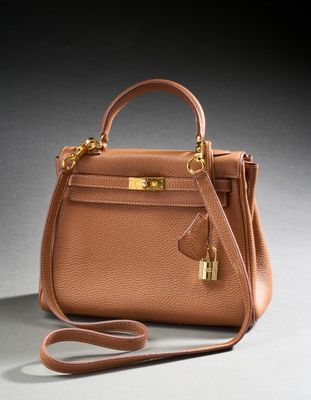 a brown leather handbag with gold hardware on a grey background
