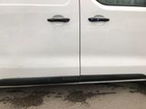 the side of a white van parked in a lot next to a building