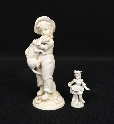 a white figurine of a boy holding a bird next to a small figurine of a boy