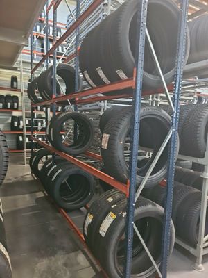 Les pneus sont empilés sur un rayonnage dans un entrepôt dont les étagères sont remplies de pneus.
