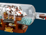 a lego ship in a glass bottle with a wooden base