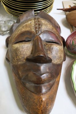 un masque en bois posé sur une table à côté d'assiettes