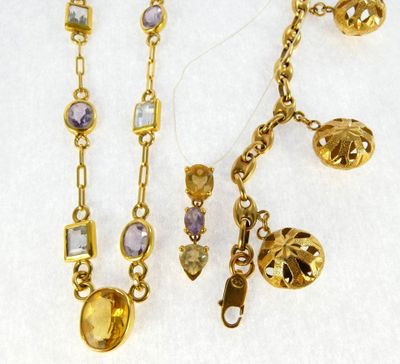 two gold tone necklaces with various colored stones on a white surface