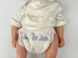 a baby doll that is laying down on a white surface