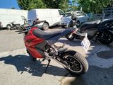 a red motorcycle parked in a parking lot next to a white van