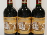 three bottles of red wine are lined up on a white surface