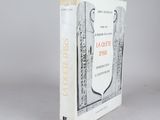 un vieux livre posé sur une table à côté d'un mur blanc