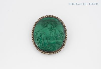 un gros plan sur une broche représentant une femme en robe verte