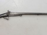 un vieux fusil avec une poignée en bois sur une surface blanche