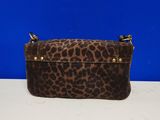 the small leopard print bag is sitting on a white table