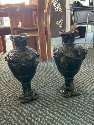 two black vases sitting on the floor in a room