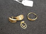 two gold rings and a pair of earrings on a black surface