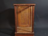 une vieille horloge en bois posée sur un socle, sur fond noir