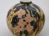 a small vase with flowers on it on a white surface