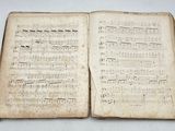an old open book with music notes on it sitting on a table