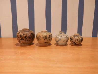 trois vases posés sur une table en bois, avec un mur rayé en arrière-plan