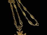 a close up of a gold necklace with a cross on it