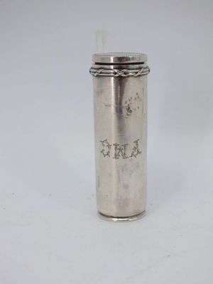 an old silver cup with a straw in it on a white surface
