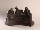 une statue en bronze représentant un groupe de personnes assises à une table