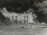 photographie en noir et blanc d'un cuirassé à l'eau, d'où s'échappent des nuages de fumée