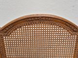 a wooden chair with a wicker back and a white wall in the background