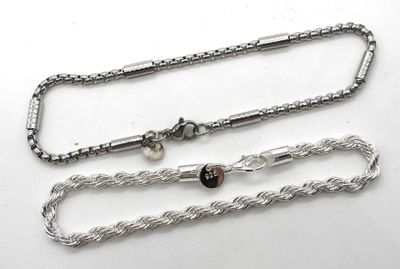 two silver chains on a white surface with a black bead