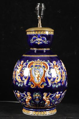 a blue vase with a gold trim and a lamp on top of it