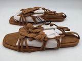 une paire de sandales marron à semelles blanches posées sur une surface blanche