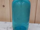 une bouteille en verre bleue posée sur un plan de travail en marbre